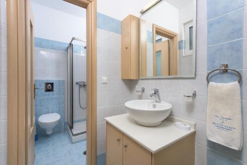 La salle de bains est pourvue d'un lavabo blanc et de toilettes. dans l'établissement Vlycha Beach Apartments, à Lindos