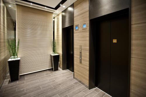 a hallway with a black door and two potted plants at Sotetsu Fresa Inn Chiba Kashiwa in Kashiwa