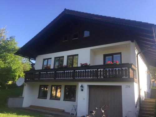a white house with a balcony on top of it at Ferienwohnung Am Sonnenhang in Strobl