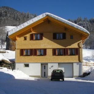 a car parked in front of a house in the snow at Appartement Bischof in Schoppernau