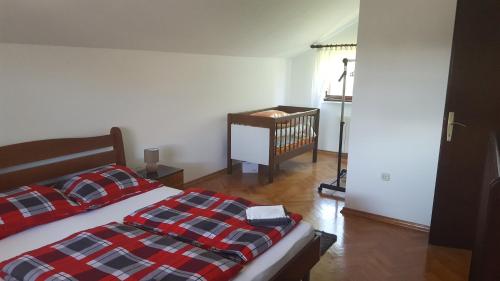 ein Schlafzimmer mit einem Bett mit einer karierten Decke und einem Kinderbett in der Unterkunft Kuća za odmor Požeg in Stubicke Toplice