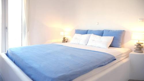 プラカにあるEvriali Beachfront Luxuryのベッドルーム(青と白のベッド1台、窓付)