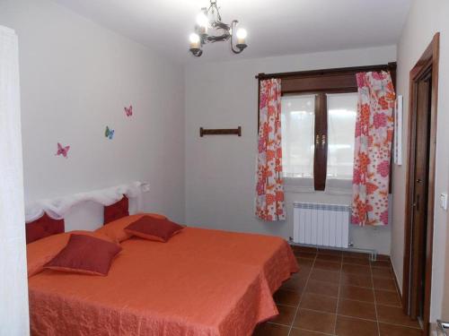 a bedroom with a bed with an orange bedspread and a window at Atxispe Etxea Casa Rural in Laukiz
