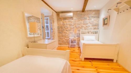 a bedroom with two beds and a stone wall at Holiday Home The Old Vine in Perast