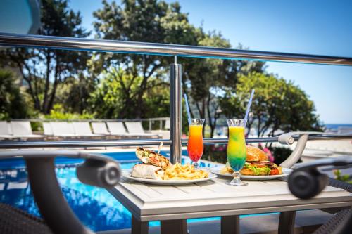 two plates of food on a table next to a pool at Royal Neptun Hotel in Dubrovnik