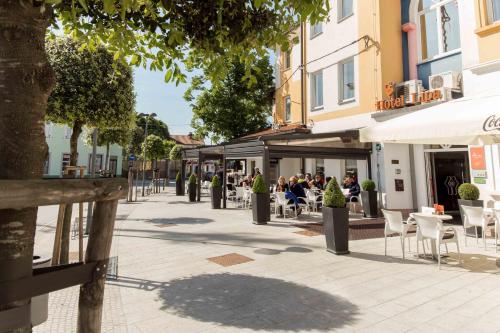 a street with tables and chairs and people sitting outside a building at Lipa, Hotel & Bistro in Nova Gorica