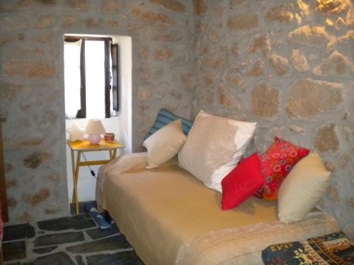 a bedroom with a couch with pillows and a stone wall at Casa da Bemposta in Bemposta