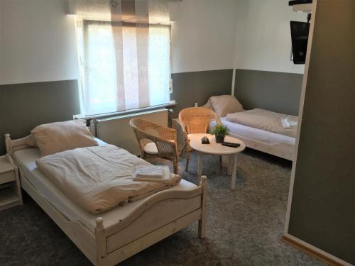 1 dormitorio con 2 camas, mesa y ventana en Landgasthof Drei Eichen, en Wilnsdorf