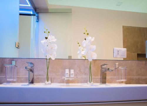 een badkamer met drie wastafels met witte bloemen erin bij Relais Dolcevita in Rome