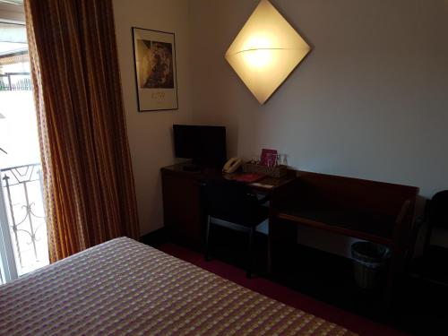 a bedroom with a desk and a bed and a lamp at Cangrande Hotel in Lazise