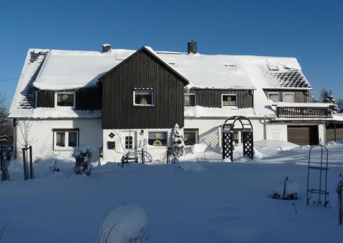 a house covered in snow with a playground at Ferienwohnung-Kubis in Kurort Altenberg