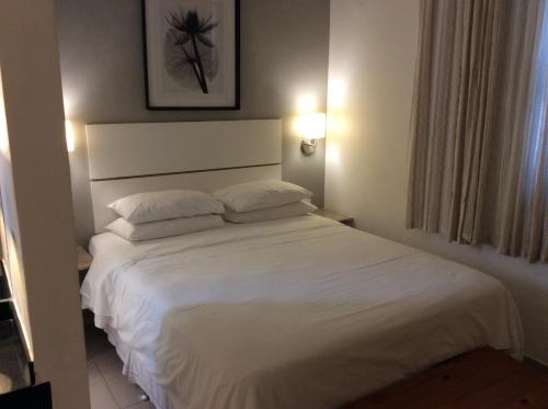 um quarto com uma grande cama branca e 2 almofadas em Ipa Penthouse Prudente no Rio de Janeiro