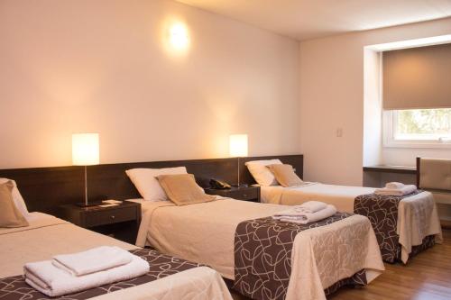 a hotel room with three beds and a window at Hotel Malargue in Malargüe