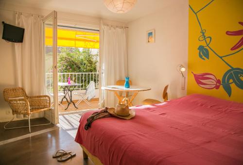 1 dormitorio con cama roja, mesa y patio en Le Val Duchesse Hotel & Appartements, en Cagnes-sur-Mer