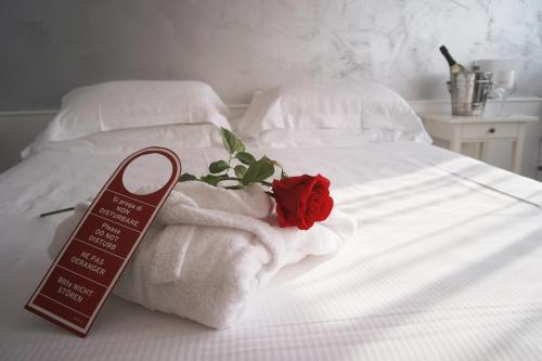 サン・ピエトロ・イン・カリアーノにあるHotel Valpolicella Internationalのベッド(タオル付)と赤いバラが付いています。