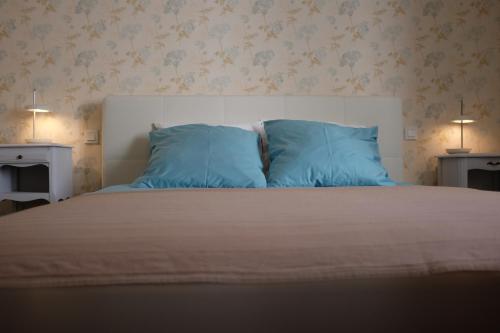 a bedroom with a bed with blue pillows at Villa Mons in Pontorson