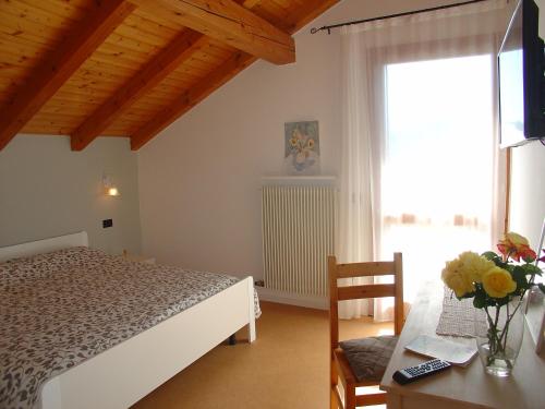 a bedroom with a bed and a table and a window at Casa Solaris in Fai della Paganella