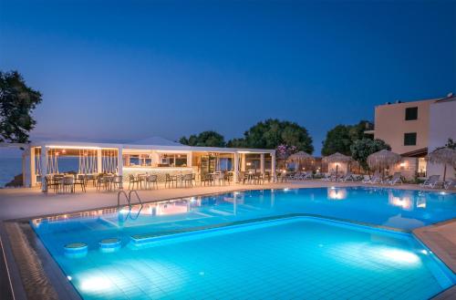 a swimming pool at night with a hotel in the background at Alexia Beach Hotel in Agia Marina Nea Kydonias