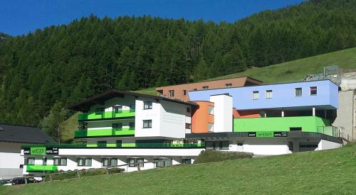 a building on a hill with trees in the background at Apart Hotel Garni Wieser in Sölden