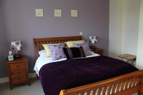 a bedroom with a bed with purple sheets and pillows at Luachra Lodge in Killarney