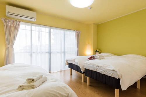 two beds in a room with a window at Ogi-Ohashi Apartment in Tokyo