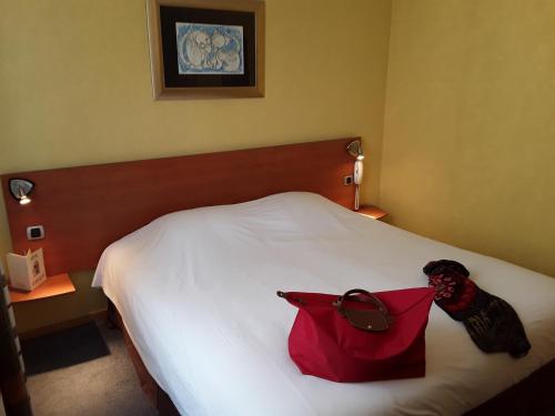 a room with a bed with a red bag on it at In Situ Hotel in Valenciennes