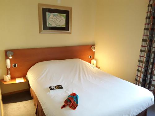 a bed in a hotel room with a towel on it at In Situ Hotel in Valenciennes