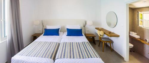 2 Betten in einem Zimmer mit einem Schreibtisch und einem Spiegel in der Unterkunft Ansi Studios & Apartments in Almyrida