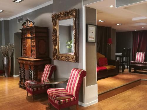sala de estar con 2 sillas y espejo en Hotel Claude Bernard Saint-Germain, en París