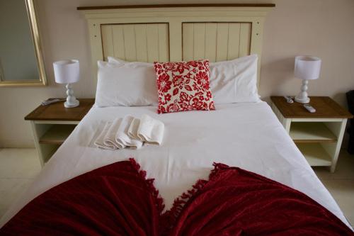 a large white bed with two tables and two pillows at Divine Guest Lodge in Rustenburg