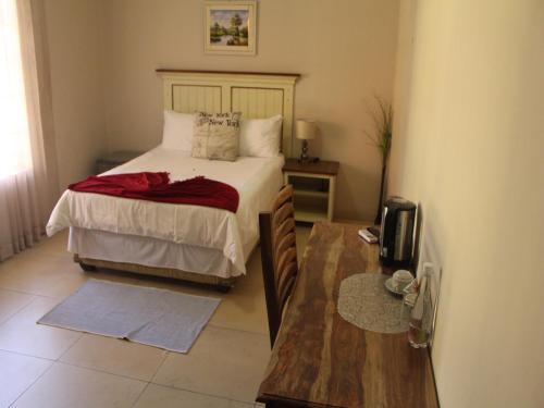a bedroom with a bed and a wooden table at Divine Guest Lodge in Rustenburg