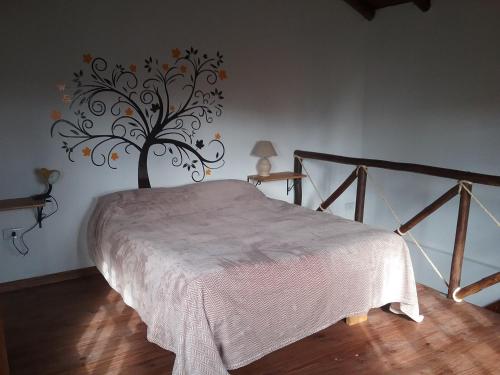 - une chambre avec un lit et un arbre sur le mur dans l'établissement El Alamo, à Sierra de la Ventana