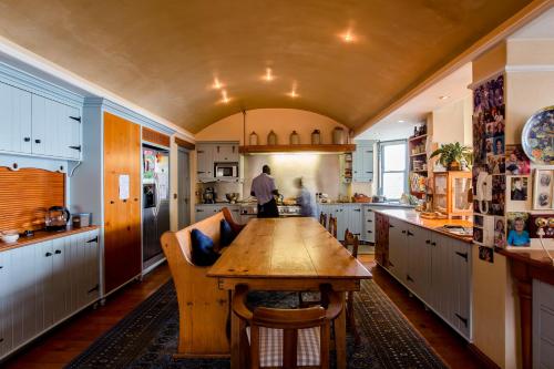 a man standing in a kitchen with a wooden table at Villa Pescatori in Yzerfontein