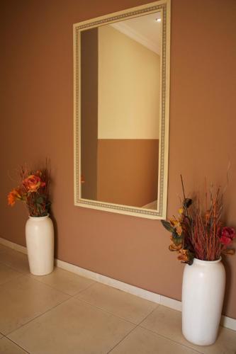 two white vases with flowers in front of a mirror at Divine Guest Lodge in Rustenburg