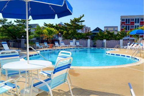een zwembad met stoelen en een tafel en een parasol bij Adams Ocean Front Resort in Dewey Beach