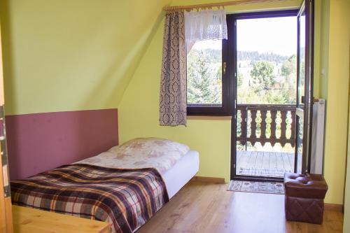 ein Schlafzimmer mit einem Bett und einem großen Fenster in der Unterkunft Hacjenda - Apartamenty i Pokoje Gościnne in Czarna Góra