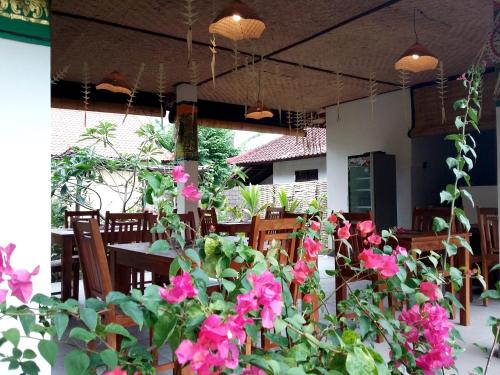a dining room with pink flowers and a table at Mango Moon in Pemuteran