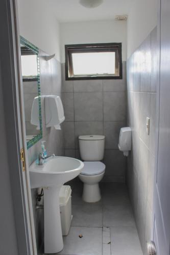 a white bathroom with a toilet and a sink at Hostel de los Colores in Piriápolis