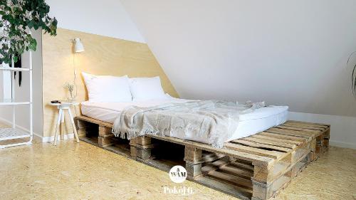 a bed sitting on a wooden bench in a room at WAM Rooms in Giżycko