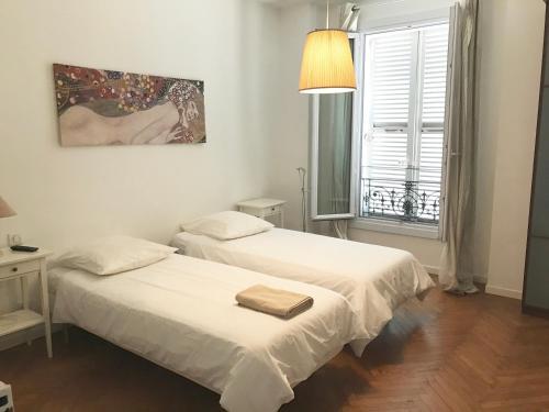 deux lits dans une petite pièce avec une fenêtre dans l'établissement Cannes Festival, à Cannes