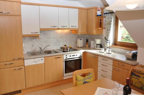 a kitchen with wooden cabinets and a sink and a table at Apartments Bogensperger in Mariapfarr