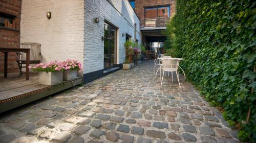 a stone walkway with a table and chairs on a patio at Gastenkamers UitGaanSlapen in Nieuwpoort