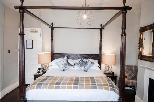 a bedroom with a canopy bed with two lamps at Hinds Head in Aldermaston