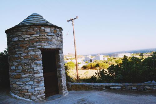 a stone fireplace with a door in a field at Stelios Zalonis Apartments in Tinos Town