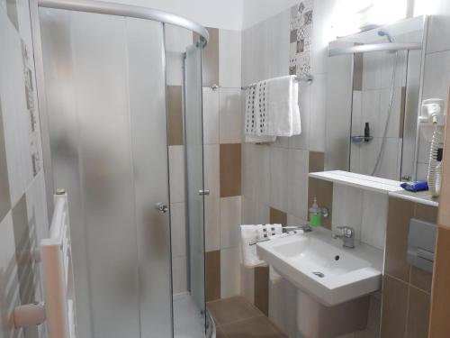 a white bathroom with a shower and a sink at Apartament Anatol in Sibiu