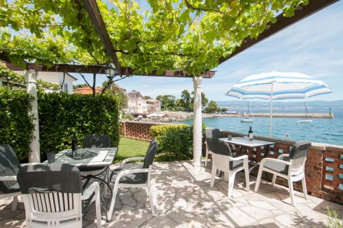 a patio with tables and chairs and a view of the water at Apartmani Belsito in Lovran