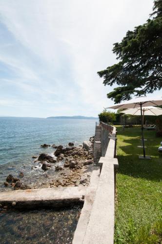 a path next to the ocean with an umbrella at Apartmani Belsito in Lovran