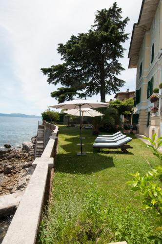 a lawn with an umbrella and benches next to a building at Apartmani Belsito in Lovran