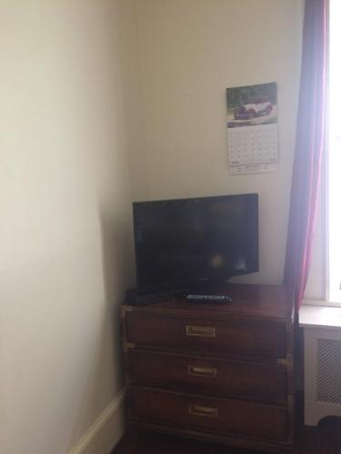 a television sitting on top of a wooden dresser at Greenwood Bed & Breakfast in Greensboro