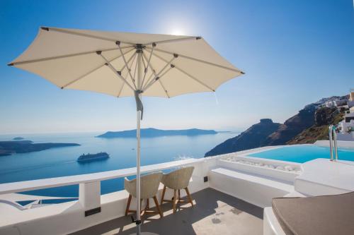 a patio with an umbrella and a swimming pool at Chic Hotel Santorini in Firostefani